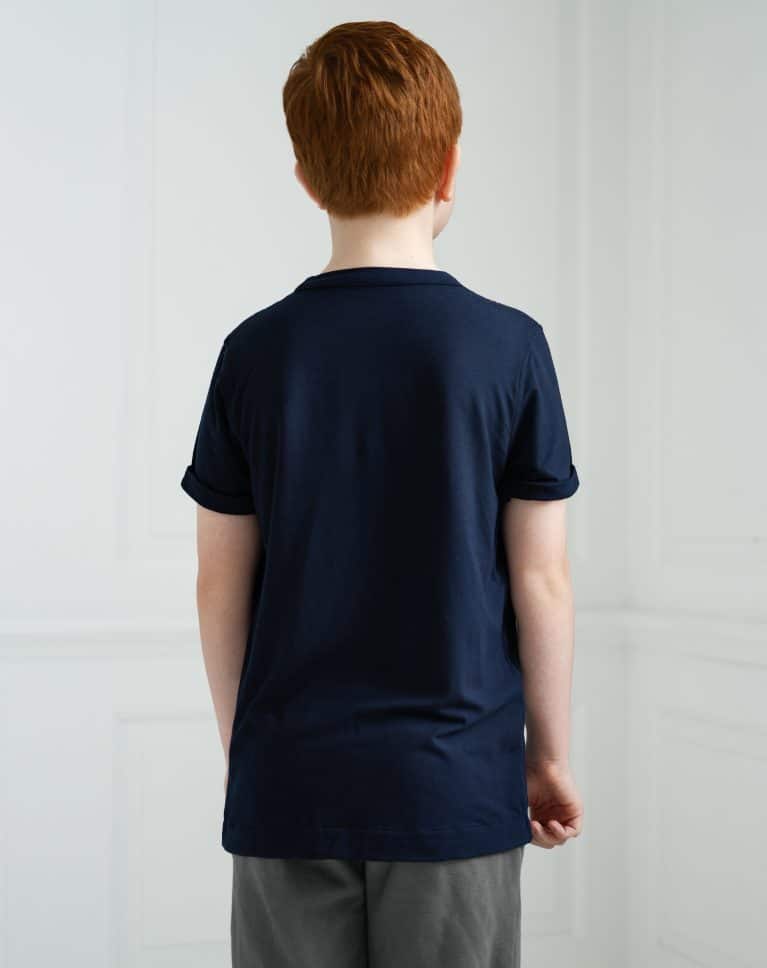 A young autistic boy with Ginger hair stands facing away from the camera, wearing a dark blue Fidget-t t-shirt